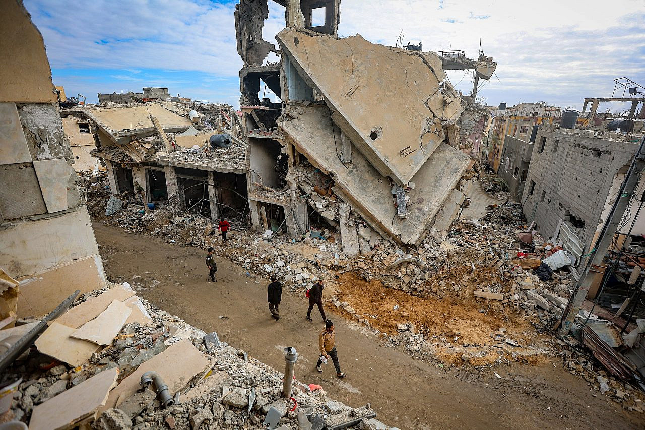 Des Palestiniens marchent à côté des décombres de bâtiments détruits par les frappes aériennes israéliennes à Khan Younis, dans le sud de la bande de Gaza, le 28 novembre 2023. (Atia Mohammed/Flash90)